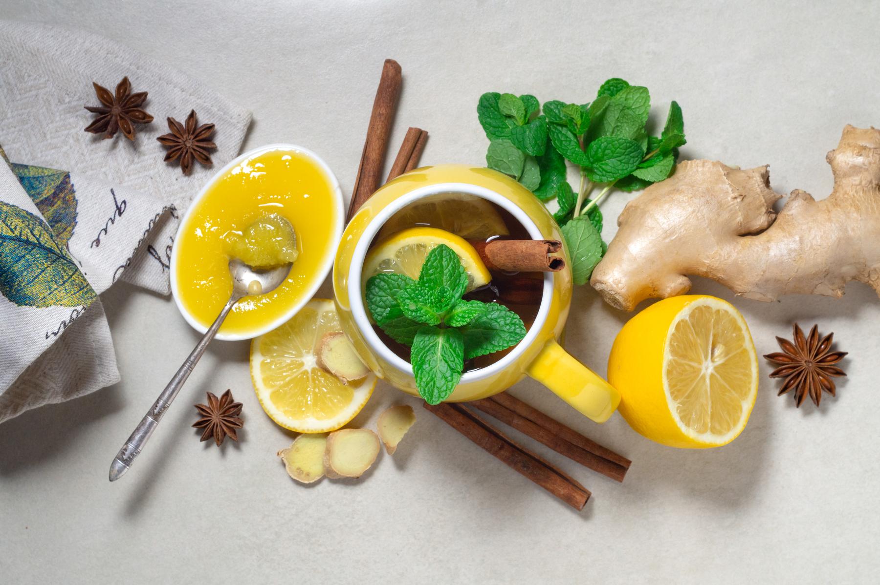 Tea with lemon, ginger, honey and cinnamon in a yellow cup and ingredients. Hot vitamin drink